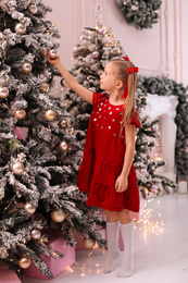 Cute little child near Christmas tree at home Photo of Cute little child near Christmas tree at home