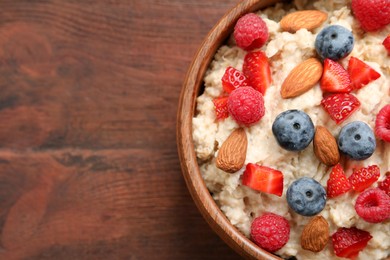 Tasty oatmeal porridge with berries and almond nuts in bowl on wooden table, top view. Space for text Photo of Tasty oatmeal porridge with berries and almond nuts in bowl on wooden table, top view. Space for text