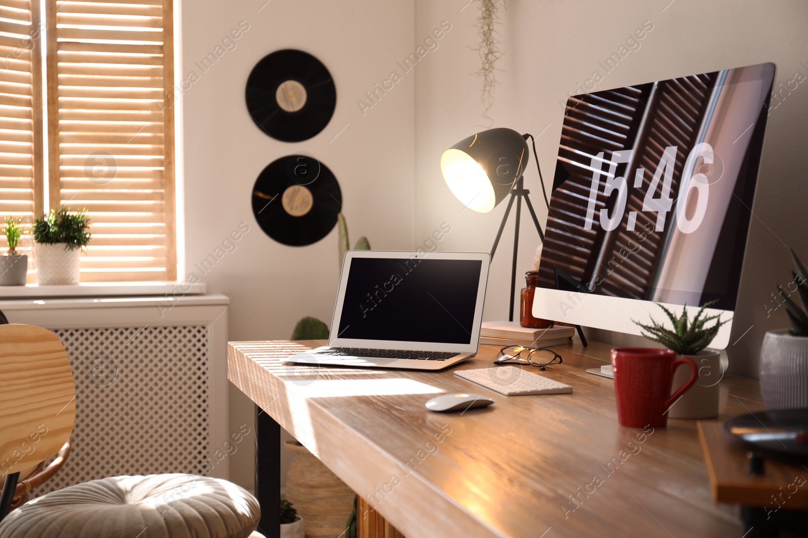 Modern computer and laptop on wooden desk in room. Interior design Photo of Modern computer and laptop on wooden desk in room. Interior design