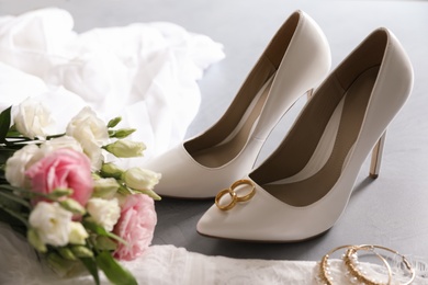 Composition with wedding dress, white high heel shoes and rings on grey background Photo of Composition with wedding dress, white high heel shoes and rings on grey background