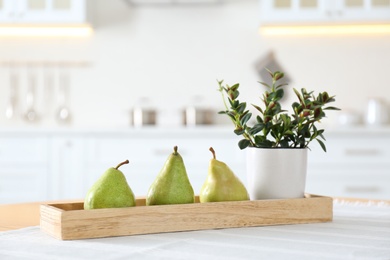 Fresh ripe pears and plant on table in kitchen Photo of Fresh ripe pears and plant on table in kitchen