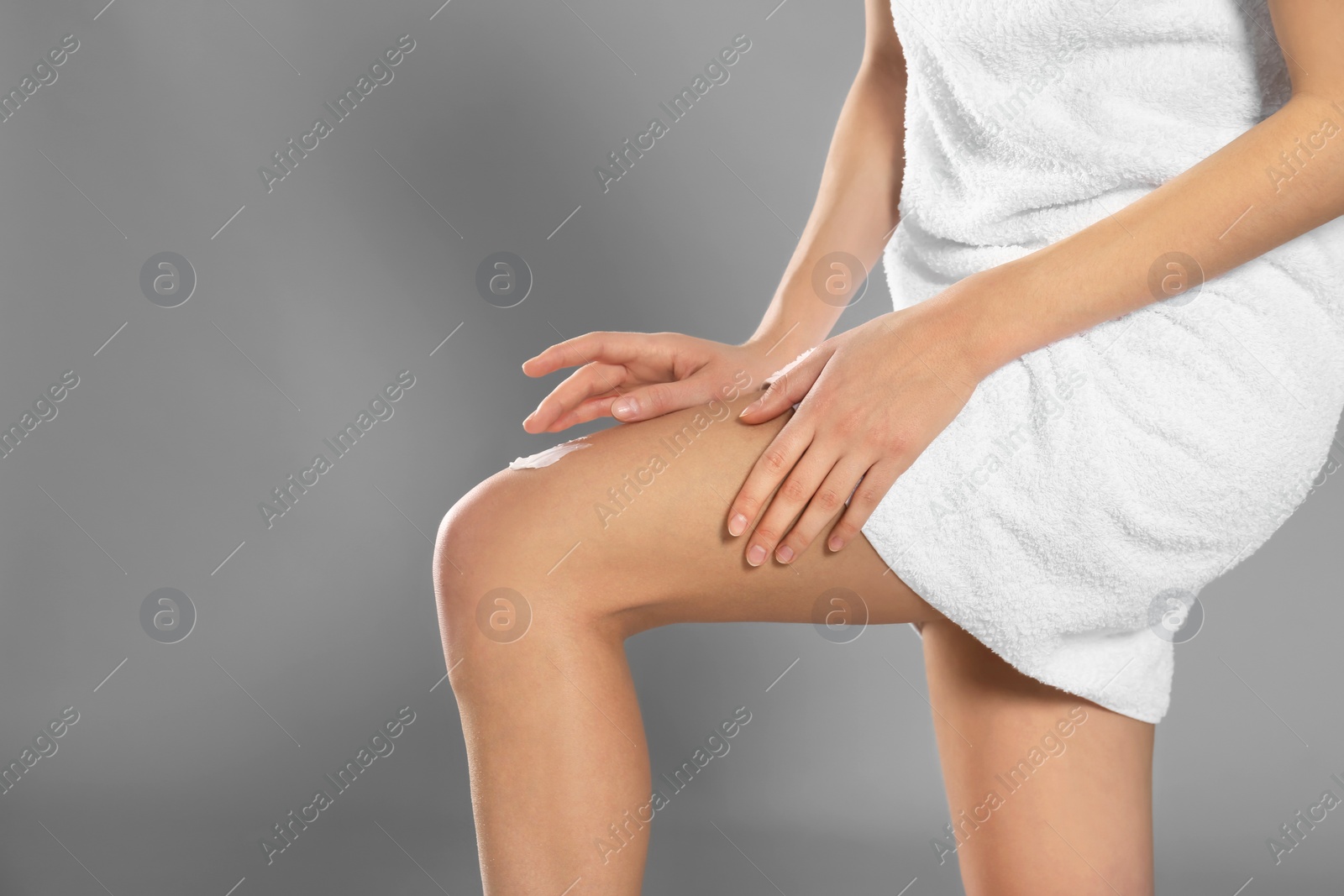 Young woman applying body cream on color background Photo of Young woman applying body cream on color background