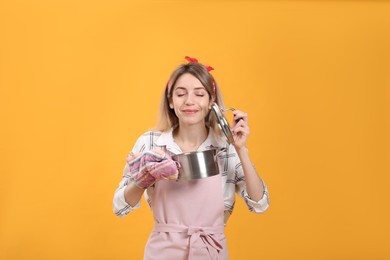 Photo of Young housewife with pot on yellow background