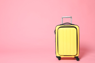 Photo of Stylish yellow suitcase on pink background. Space for text