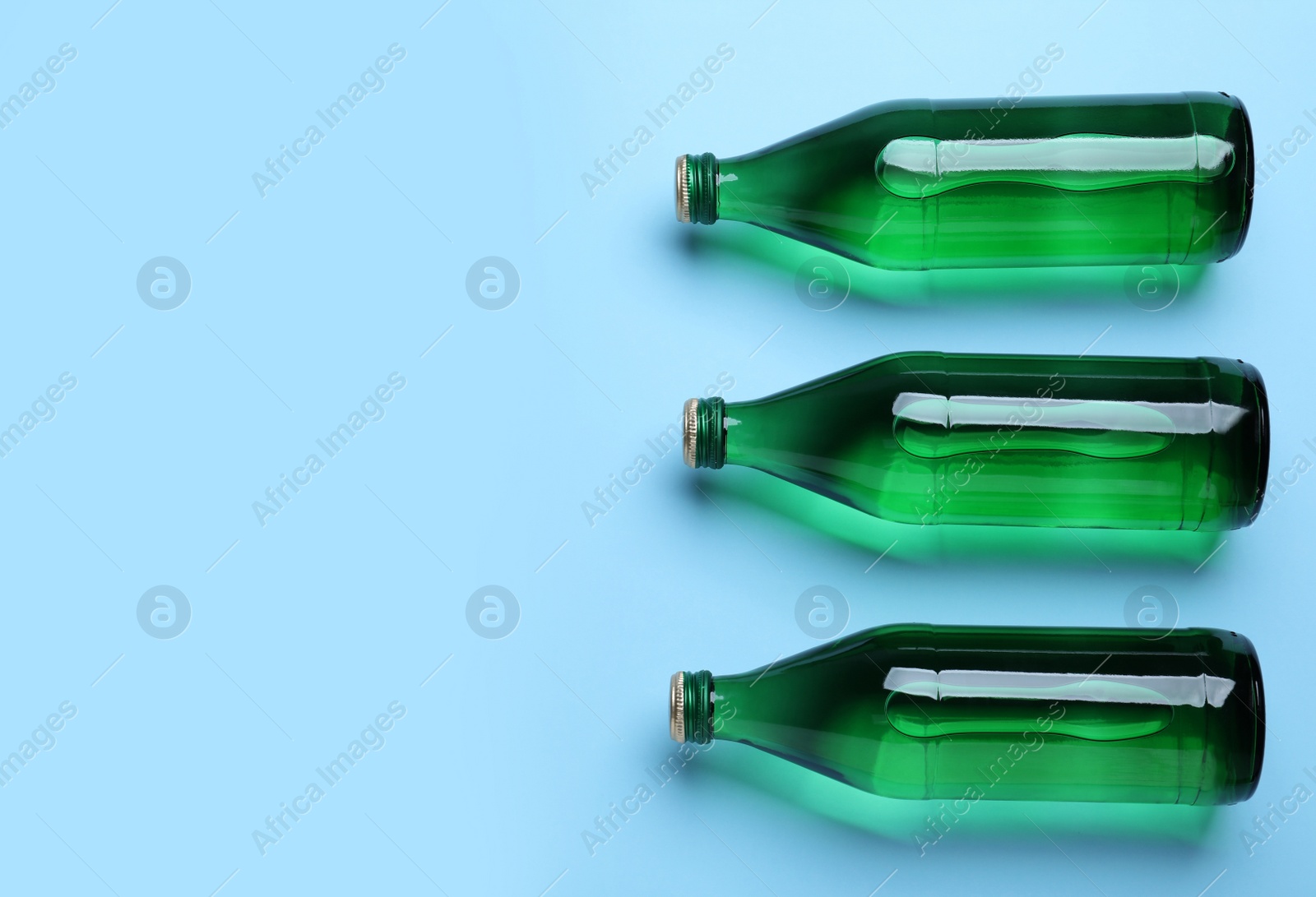 Glass bottles with water on light blue background, flat lay. Space for text Photo of Glass bottles with water on light blue background, flat lay. Space for text