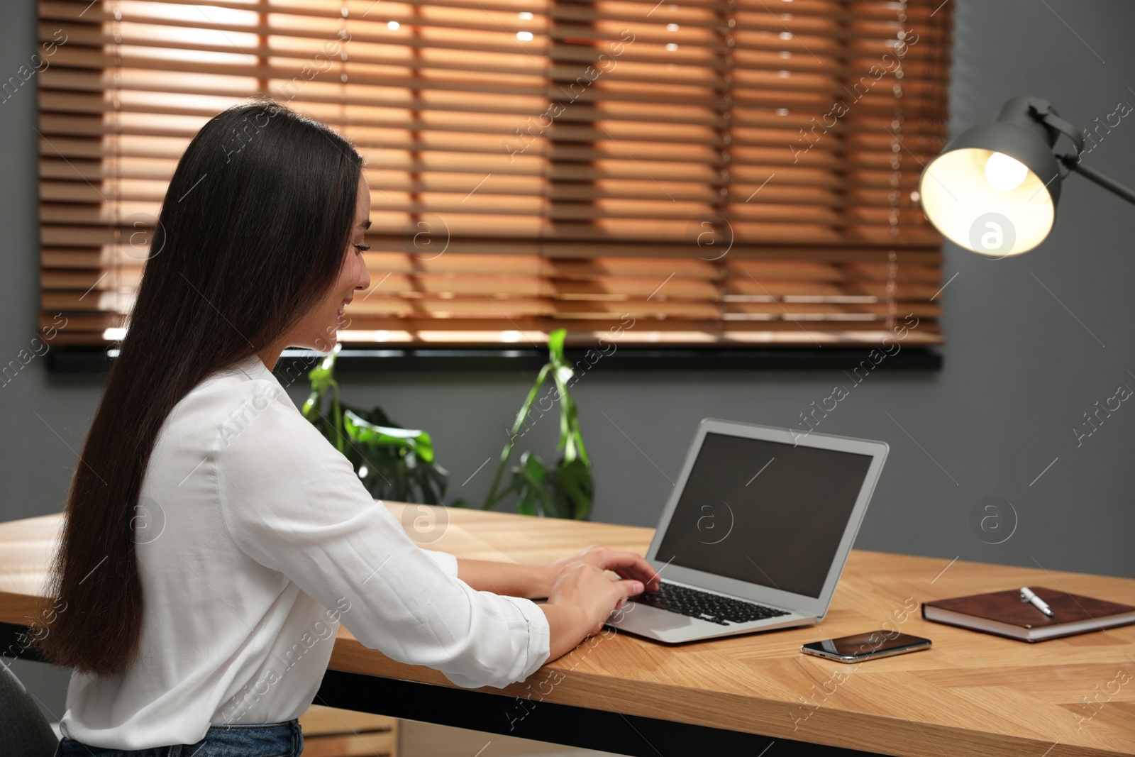 Young woman using laptop for search at wooden table in office Photo of Young woman using laptop for search at wooden table in office