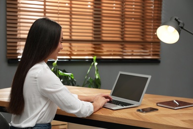 Young woman using laptop for search at wooden table in office Photo of Young woman using laptop for search at wooden table in office