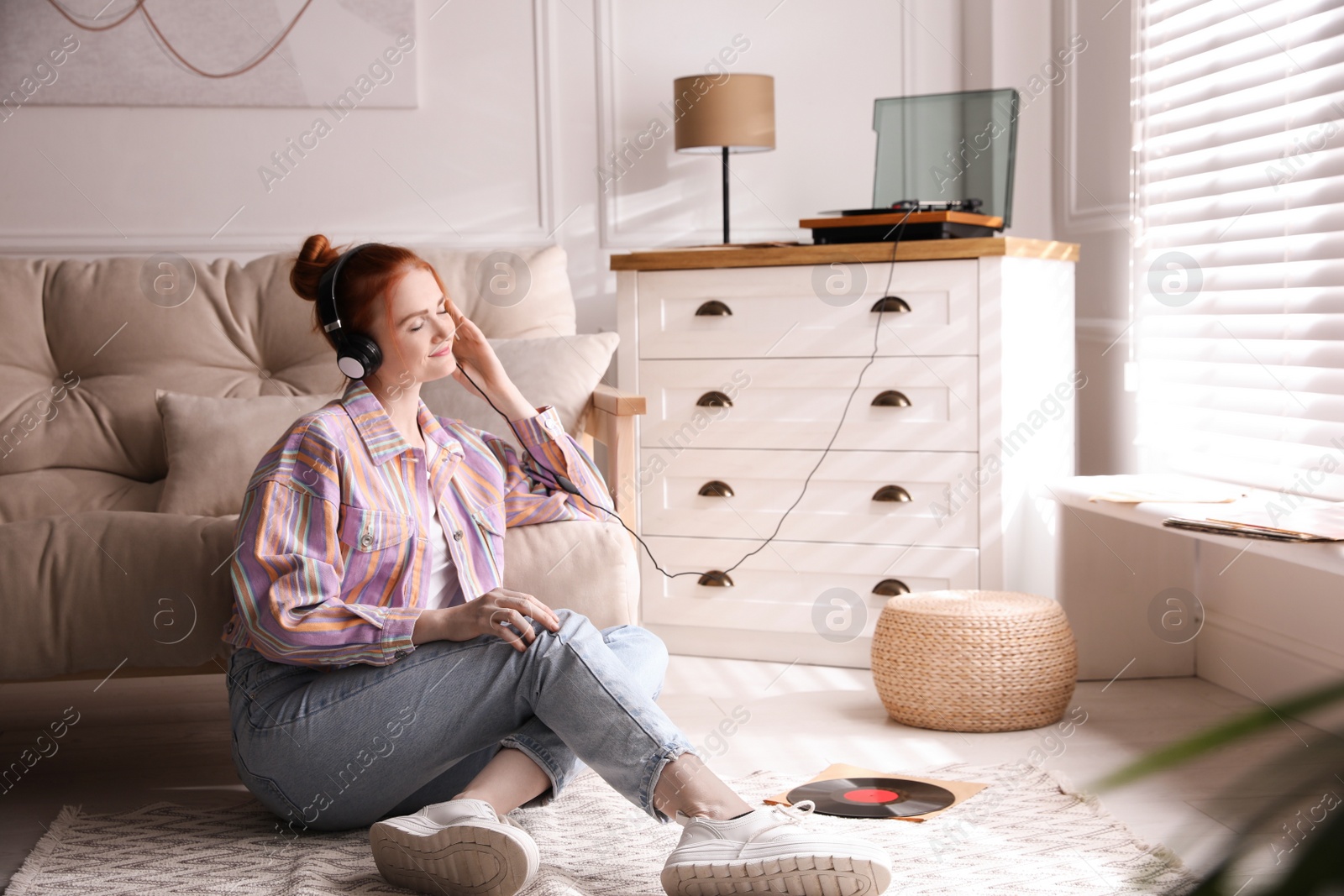 Young woman listening to music with turntable in living room Photo of Young woman listening to music with turntable in living room