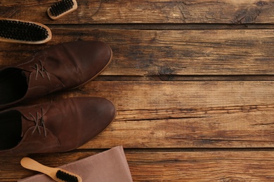 Photo of Stylish footwear with shoe care accessories on wooden table, flat lay. Space for text