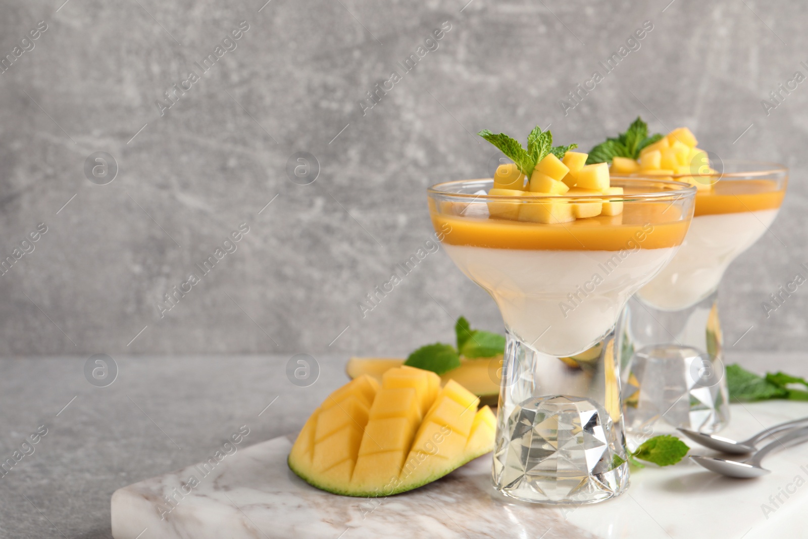 Delicious panna cotta with mango coulis served on light grey table. Space for text Photo of Delicious panna cotta with mango coulis served on light grey table. Space for text