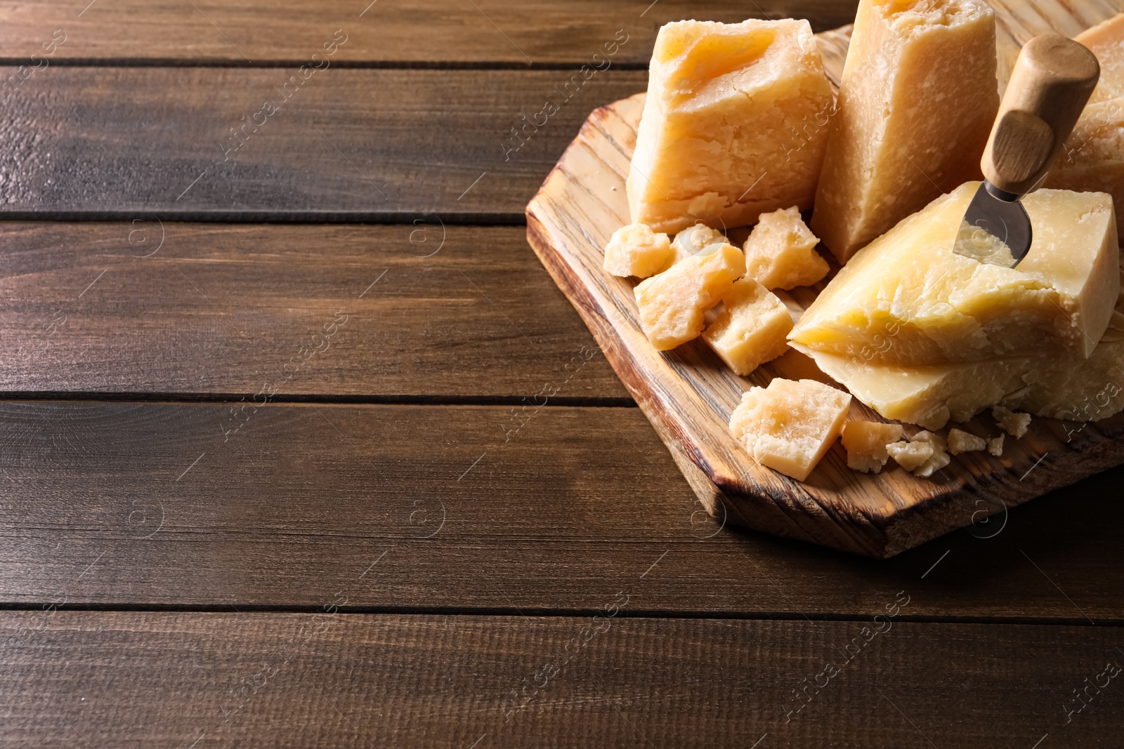 Pieces of delicious parmesan cheese with knife on wooden table. Space for text Photo of Pieces of delicious parmesan cheese with knife on wooden table. Space for text