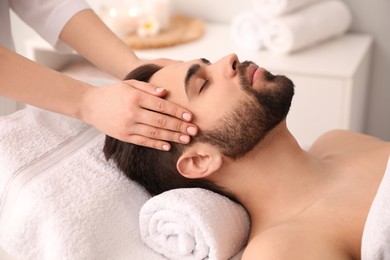 Young man receiving facial massage in beauty salon Photo of Young man receiving facial massage in beauty salon