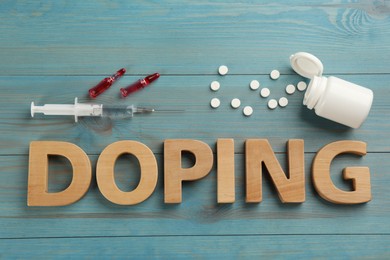 Word Doping and drugs on light blue wooden background, flat lay Photo of Word Doping and drugs on light blue wooden background, flat lay