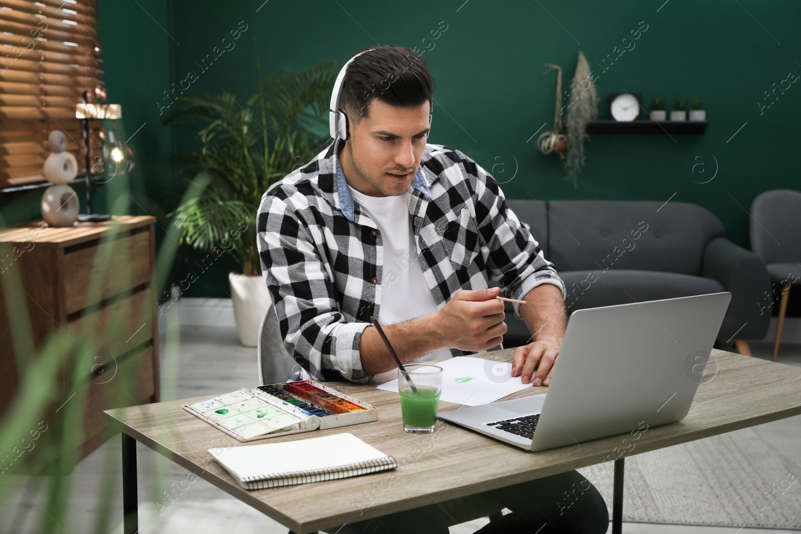 Man drawing with paints at online lesson indoors. Distance learning Photo of Man drawing with paints at online lesson indoors. Distance learning