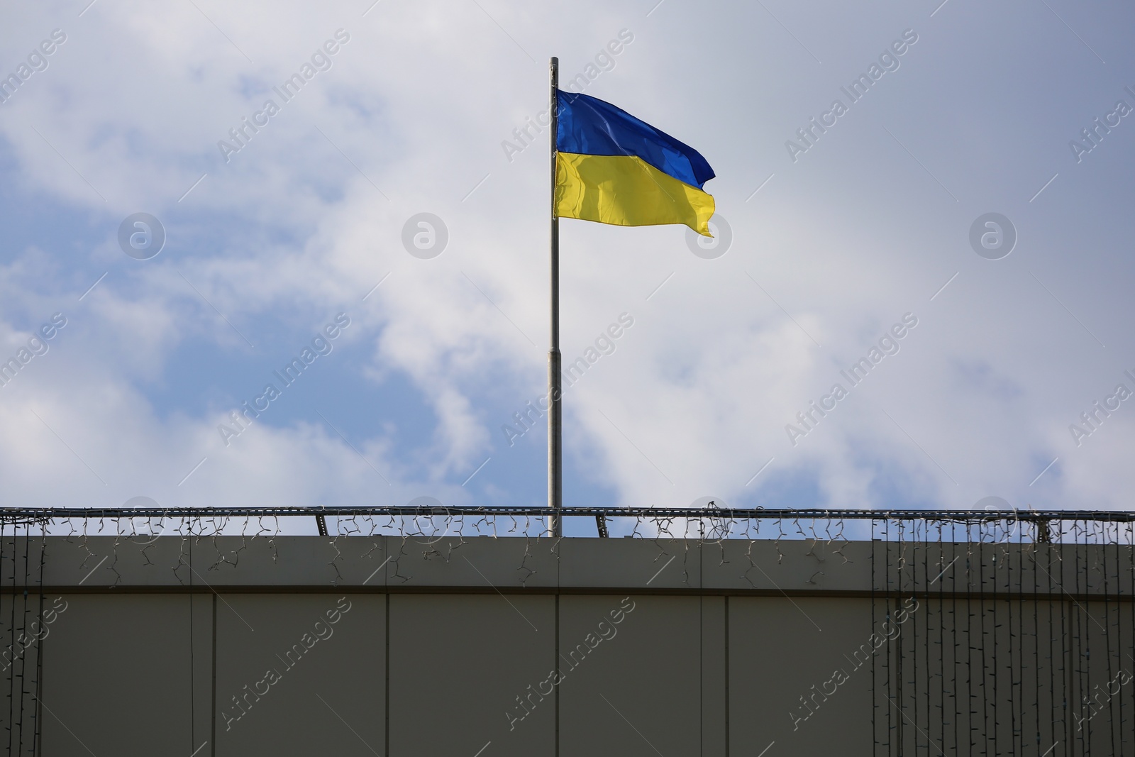 Ukrainian flag on building against cloudy sky Photo of Ukrainian flag on building against cloudy sky