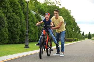 Dad teaching son to ride bicycle outdoors Image of Dad teaching son to ride bicycle outdoors