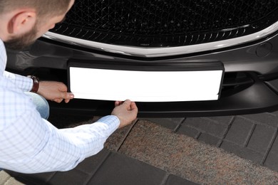 Man installing vehicle registration plate outdoors, closeup. Mockup for design Photo of Man installing vehicle registration plate outdoors, closeup. Mockup for design