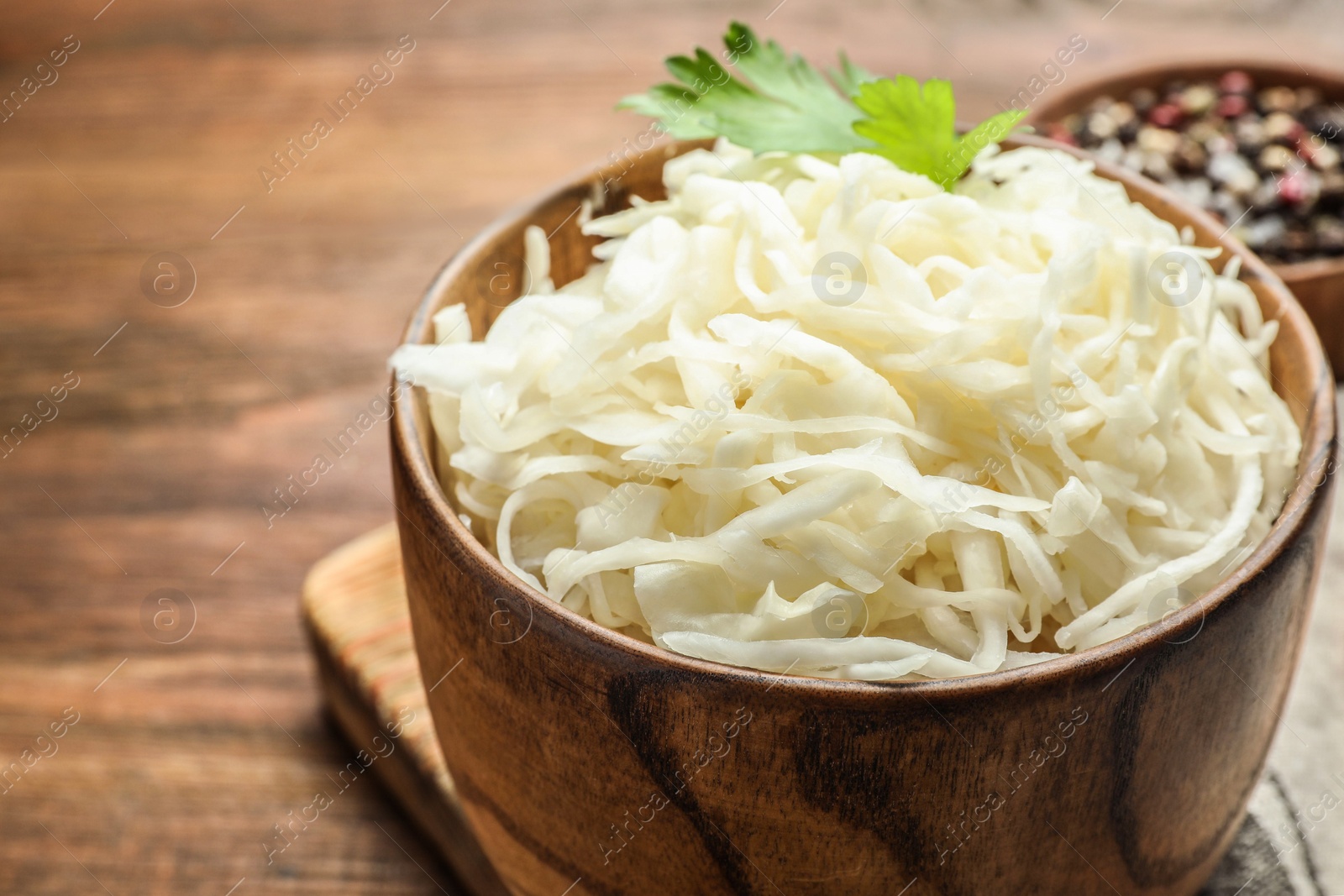 Wooden bowl of tasty fermented cabbage on table, closeup Photo of Wooden bowl of tasty fermented cabbage on table, closeup