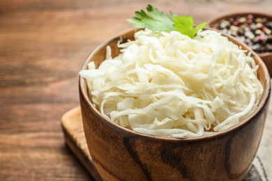 Wooden bowl of tasty fermented cabbage on table, closeup Photo of Wooden bowl of tasty fermented cabbage on table, closeup