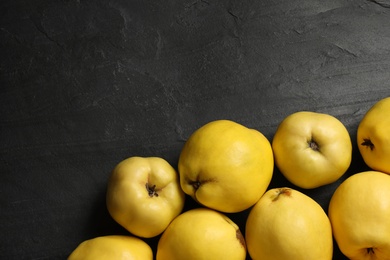 Photo of Fresh ripe organic quinces on black table, flat lay. Space for text