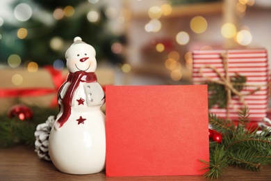 Christmas composition with decorative snowman near red blank card on table, space for text Photo of Christmas composition with decorative snowman near red blank card on table, space for text