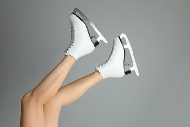 Woman in elegant white ice skates on grey background, closeup of legs Photo of Woman in elegant white ice skates on grey background, closeup of legs