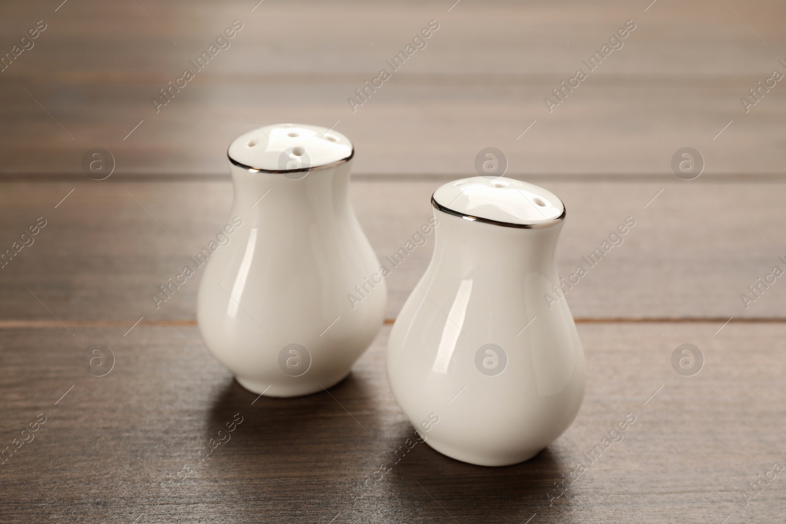 White ceramic salt and pepper shakers on wooden table, closeup Photo of White ceramic salt and pepper shakers on wooden table, closeup