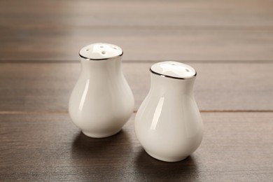 White ceramic salt and pepper shakers on wooden table, closeup Photo of White ceramic salt and pepper shakers on wooden table, closeup
