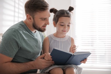Little girl with father reading fairy tale indoors Photo of Little girl with father reading fairy tale indoors