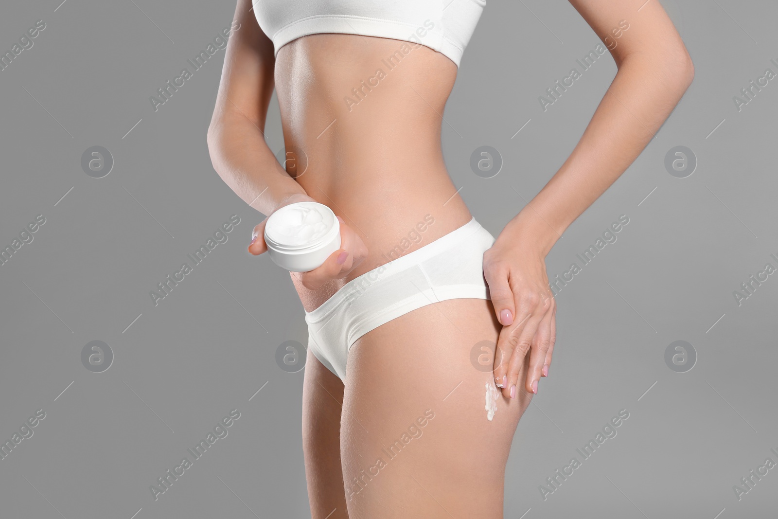 Photo of Young woman with jar of body cream on color background