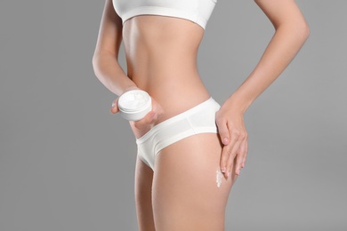 Young woman with jar of body cream on color background Photo of Young woman with jar of body cream on color background