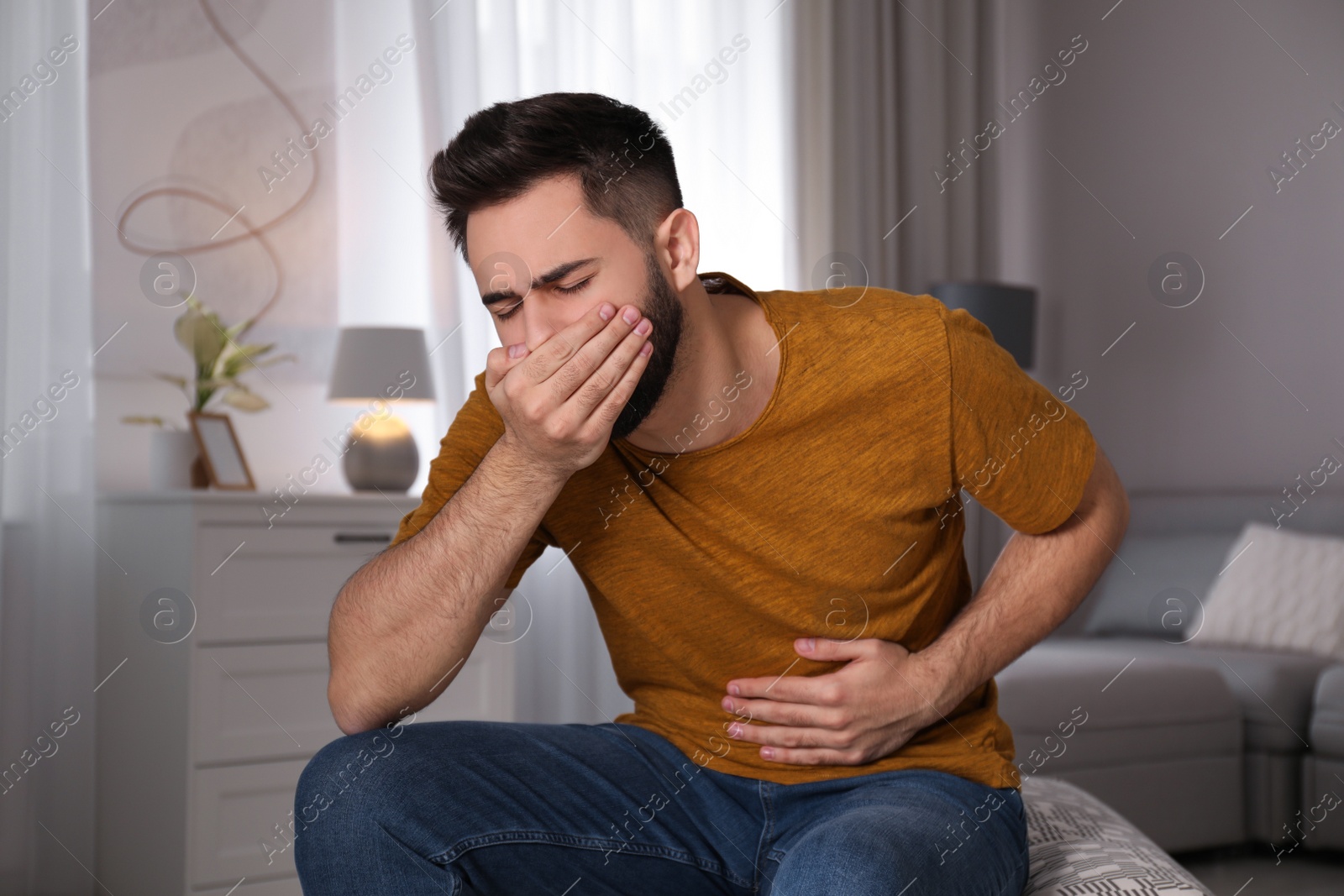 Young man suffering from nausea at home. Food poisoning Photo of Young man suffering from nausea at home. Food poisoning