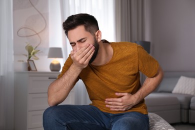 Young man suffering from nausea at home. Food poisoning Photo of Young man suffering from nausea at home. Food poisoning