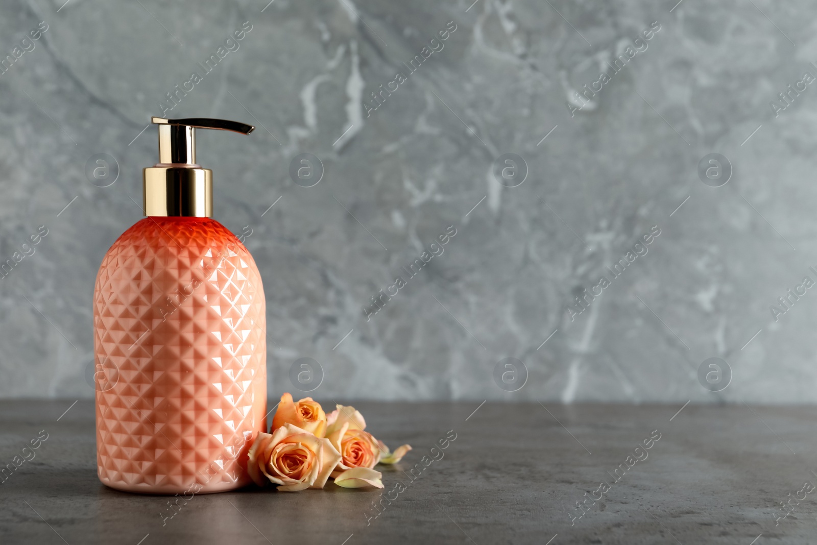 Stylish dispenser with liquid soap and beautiful flowers on grey table, space for text Photo of Stylish dispenser with liquid soap and beautiful flowers on grey table, space for text