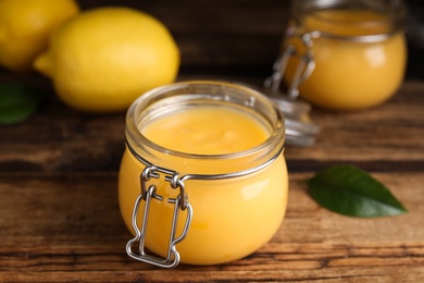 Delicious lemon curd in glass jar on wooden table Photo of Delicious lemon curd in glass jar on wooden table