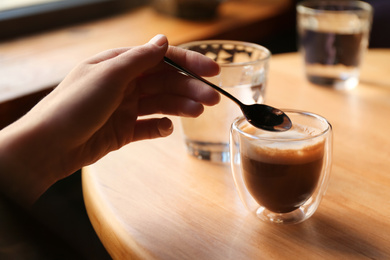 Photo of Woman with aromatic coffee at table in cafe, closeup