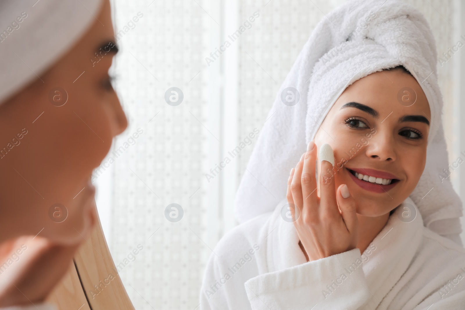 Woman using silkworm cocoon in skin care routine near mirror at home Photo of Woman using silkworm cocoon in skin care routine near mirror at home