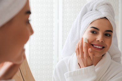 Woman using silkworm cocoon in skin care routine near mirror at home Photo of Woman using silkworm cocoon in skin care routine near mirror at home