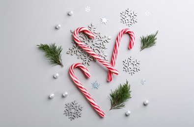 Flat lay composition with candy canes and Christmas decor on grey background Photo of Flat lay composition with candy canes and Christmas decor on grey background