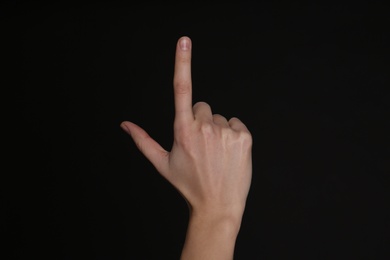 Woman pointing at something on black background, closeup. Finger gesture Photo of Woman pointing at something on black background, closeup. Finger gesture