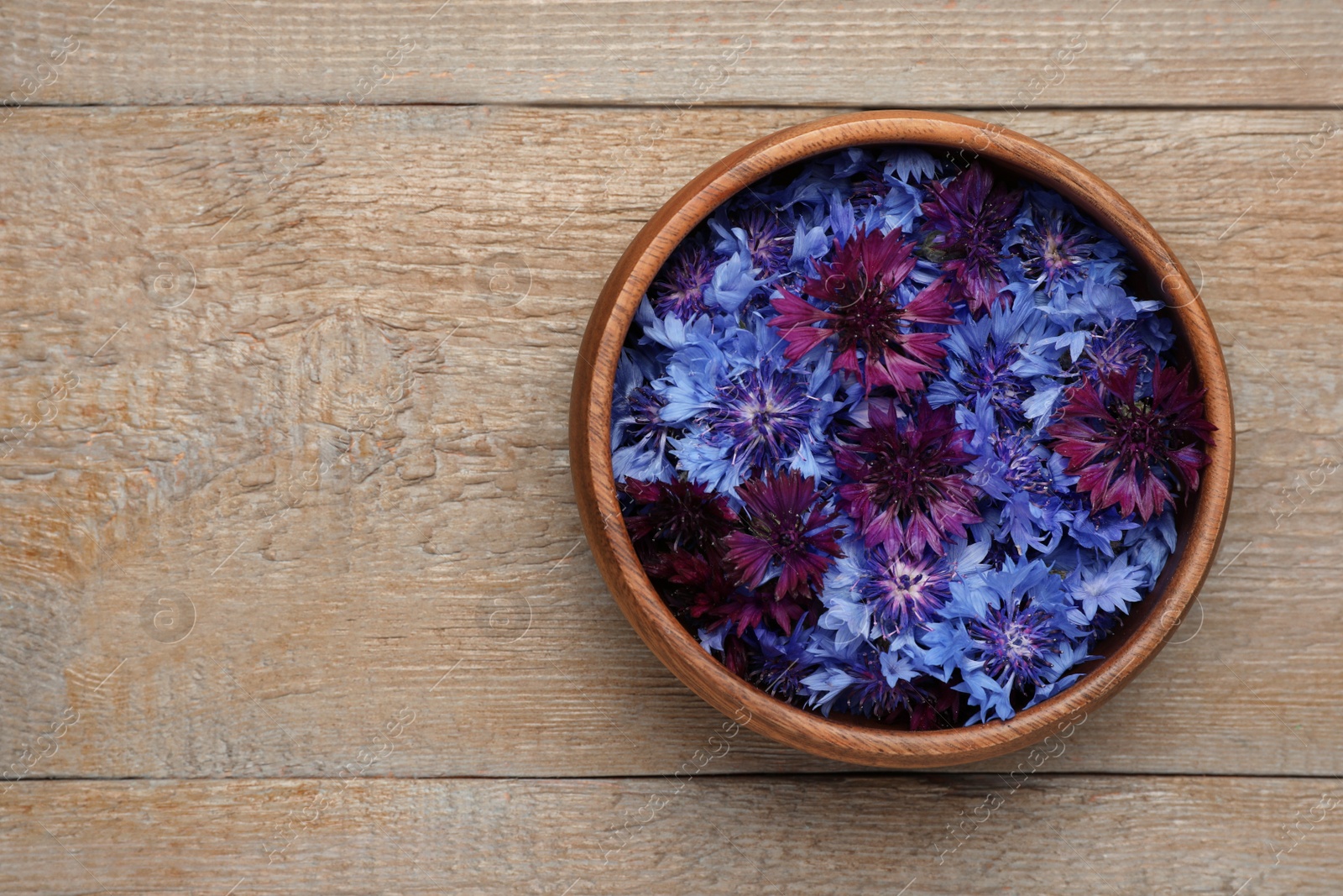 Beautiful colorful cornflowers in bowl on wooden table, top view. Space for text Photo of Beautiful colorful cornflowers in bowl on wooden table, top view. Space for text