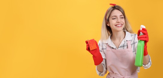 Young housewife with detergent and sponge on yellow background. Space for text Photo of Young housewife with detergent and sponge on yellow background. Space for text