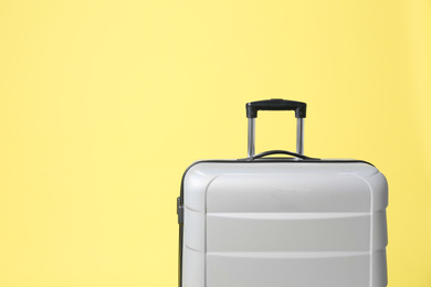 Photo of Stylish grey suitcase on yellow background. Space for text