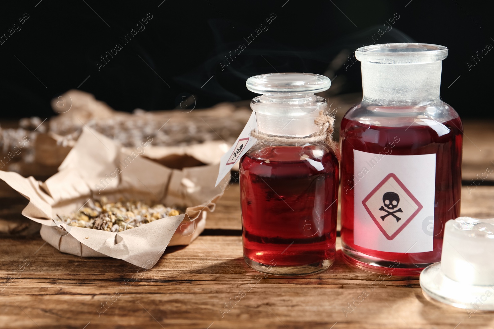 Glass bottles of poison with warning signs on wooden table Photo of Glass bottles of poison with warning signs on wooden table