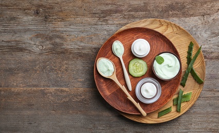 Composition with body cream in jars on wooden background, top view Photo of Composition with body cream in jars on wooden background, top view