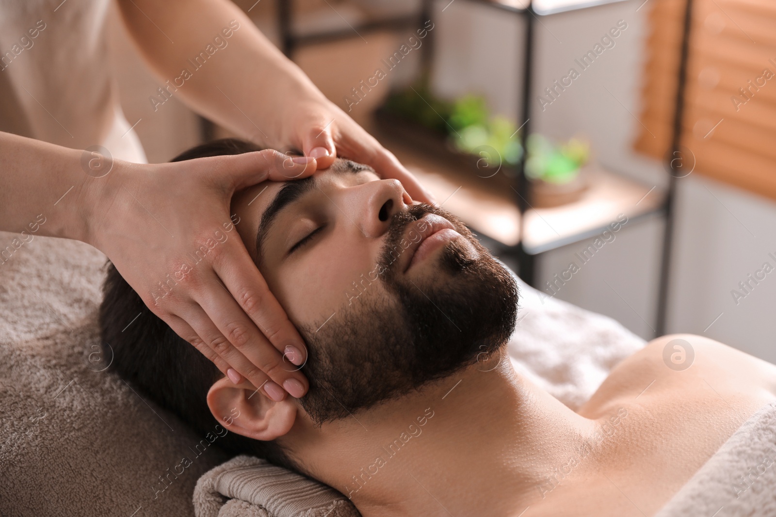 Young man receiving facial massage in beauty salon Photo of Young man receiving facial massage in beauty salon