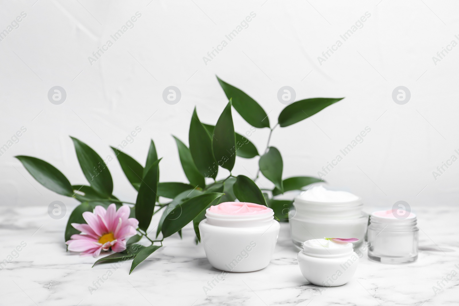Composition with body cream in jars on light background Photo of Composition with body cream in jars on light background