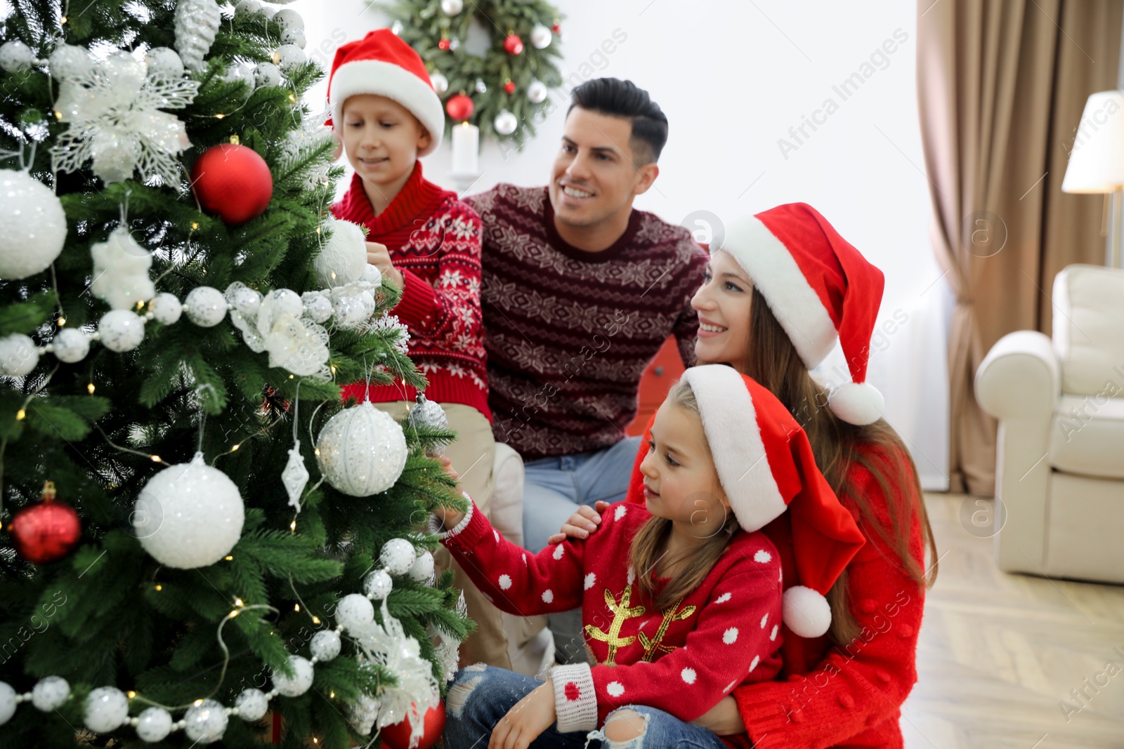 Happy family with cute children decorating Christmas tree together at home Photo of Happy family with cute children decorating Christmas tree together at home