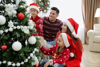 Happy family with cute children decorating Christmas tree together at home Photo of Happy family with cute children decorating Christmas tree together at home