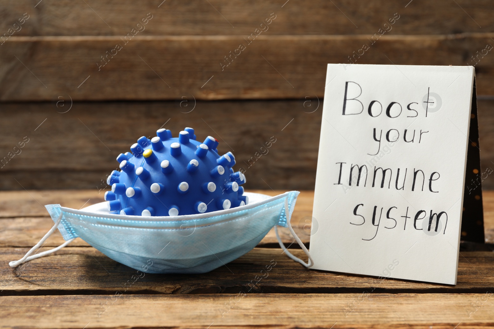 Notebook with phrase Boost your Immune System and medical mask on wooden table Photo of Notebook with phrase Boost your Immune System and medical mask on wooden table
